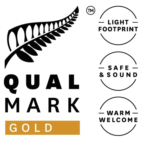 Qualmark Gold award badge in white with gold features and black text from Tourism New Zealand, recognizing Queenstown Wine Trail as a best-in-class sustainable tourism business delivering exceptional customer experiences. Highlights leadership in sustainable luxury wine and food tours across Central Otago, New Zealand.